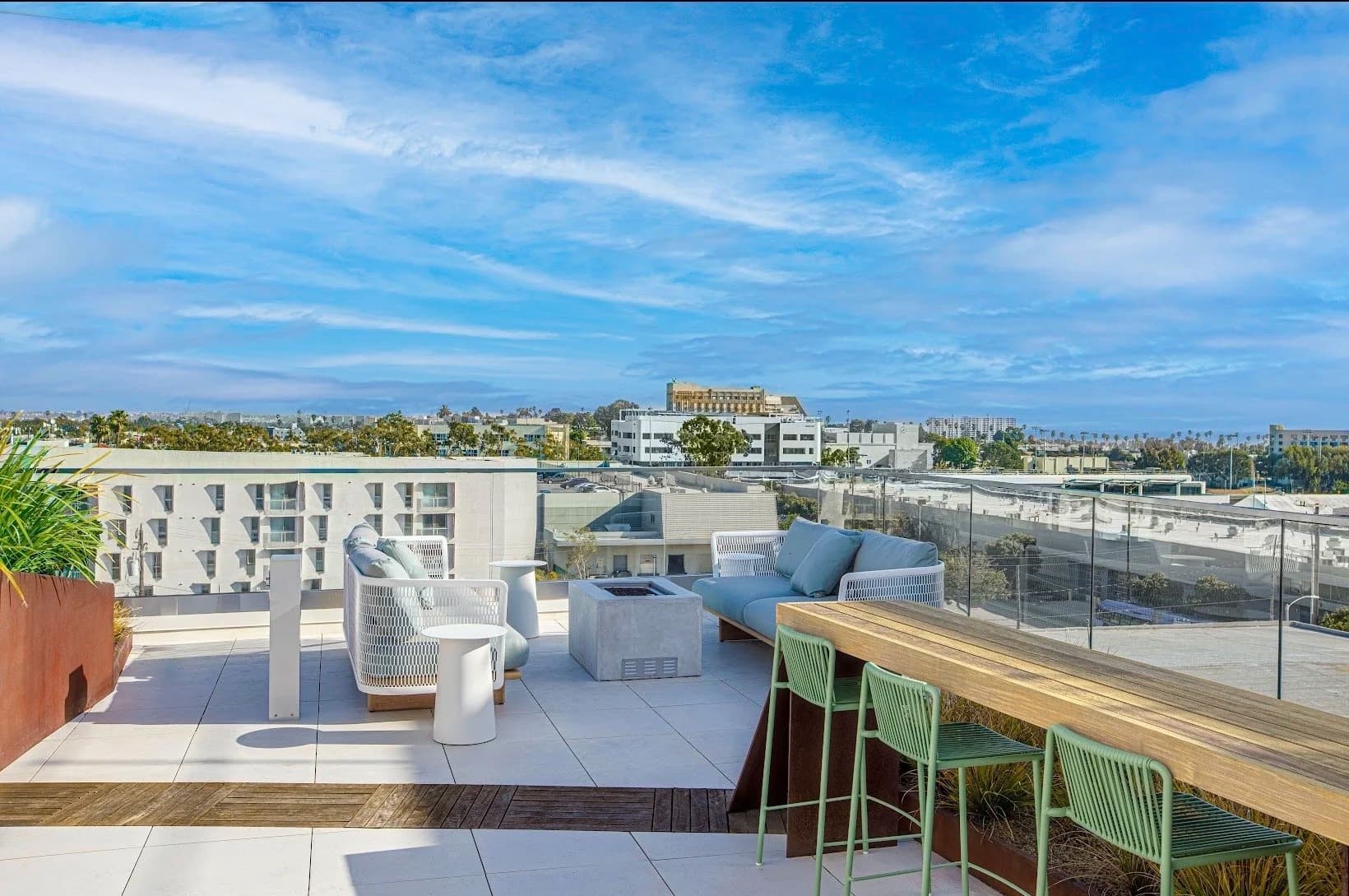 Rooftop terrace lounge with sofas and a fire pit overlooking the city