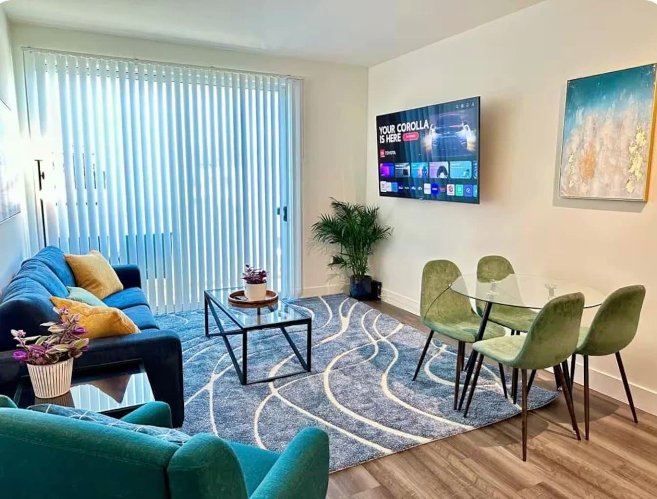Furnished living room with blue sofa, area rug, smart TV and dining set in a Santa Monica monthly rental
