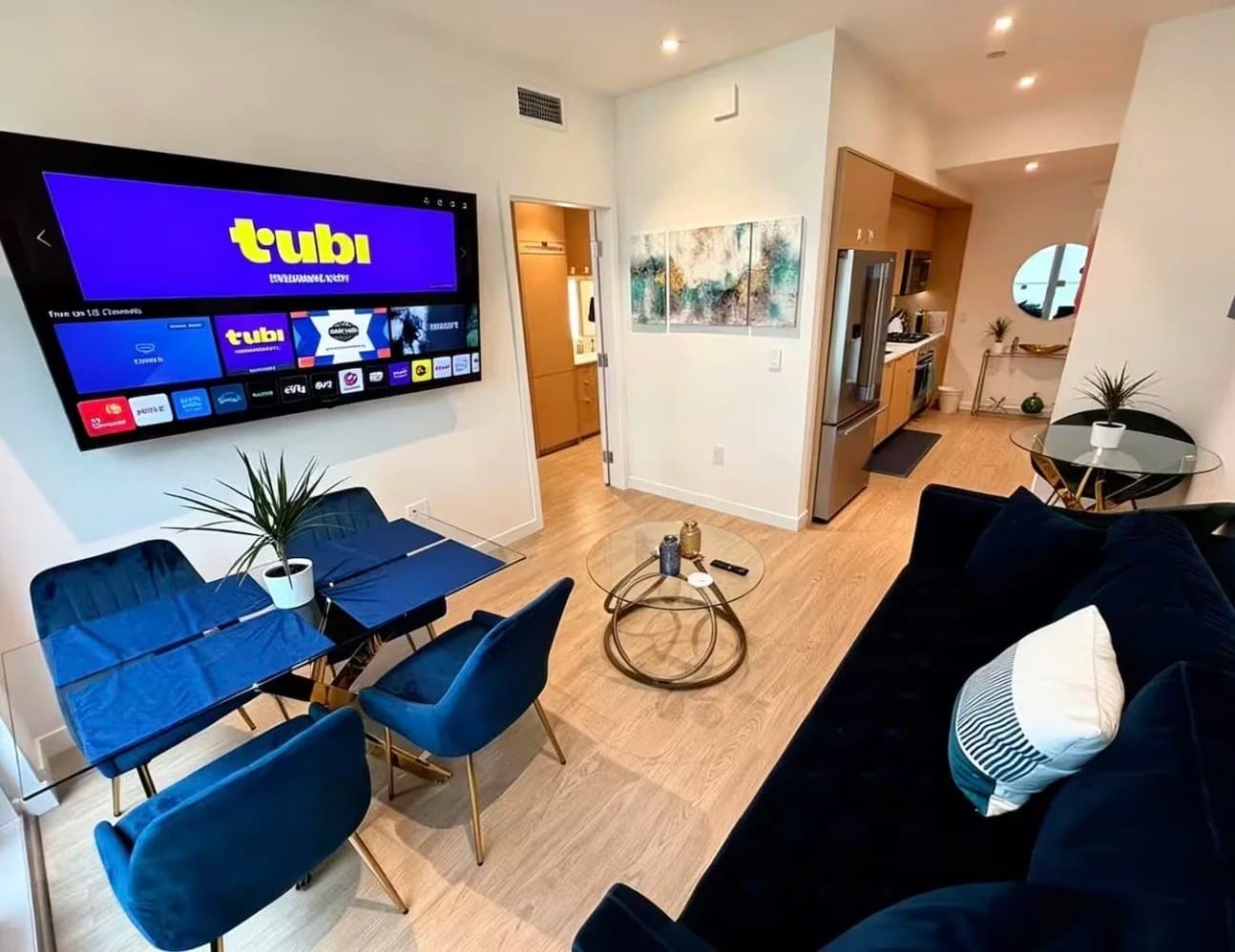 Furnished living and dining area with navy sofa, wall TV and open kitchen in a Santa Monica monthly rental