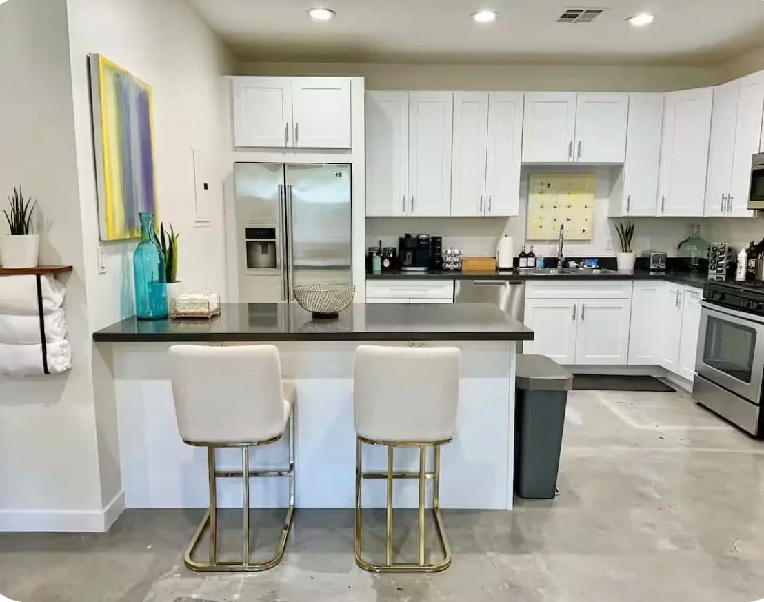 Furnished kitchen with breakfast-bar island, two stools and stainless steel appliances in a Santa Monica rental